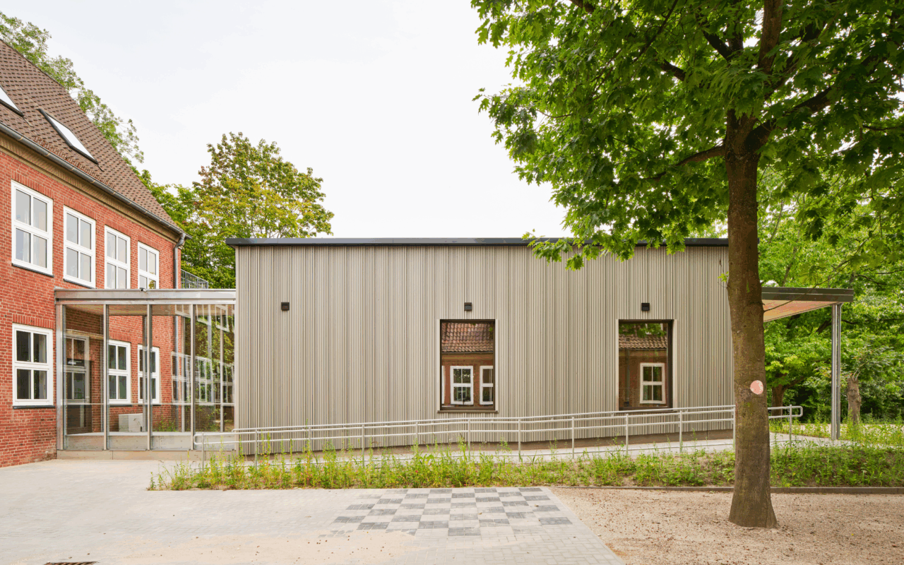 The cafeteria, with its curtain wall wooden façade, is connected to the existing building.